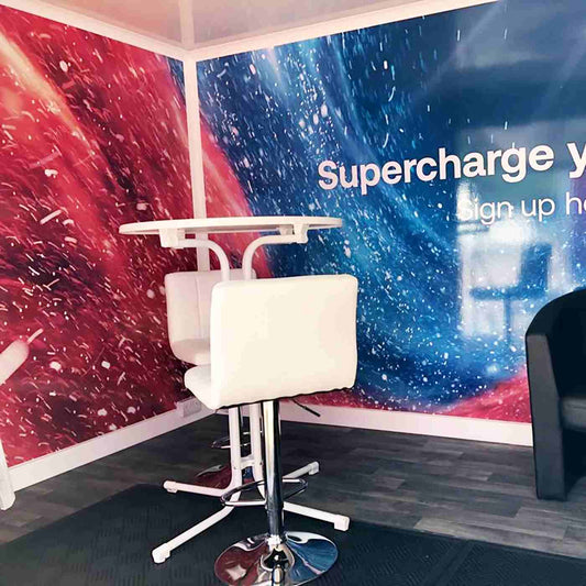 Red and blue promotional graphics behind white stools, from the Metamark MD-80 gallery.