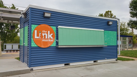 The Link market kiosk with green printed panels; SAG-family application example, exact SAG grade unverified, not a photograph of the supplied roll.